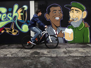 A man cycles past a wall graffiti of caricatures of U.S. President Barack Obama (L) and Cuban leader Fidel Castro outside a restaurant in Mexico City, August 21, 2012. REUTERS/ Edgard Garrido (MEXICO - Tags: TRANSPORT SOCIETY) - RTR370OW